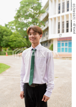 Happy non binary university student smiling in college campus Happy non binary university student smiling in college campus 128540210