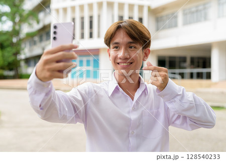 University student using phone in campus taking selfie 128540233
