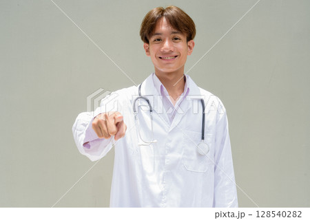 Young healthcare worker wearing lab coat pointing finger Young healthcare worker wearing lab coat pointing finger 128540282
