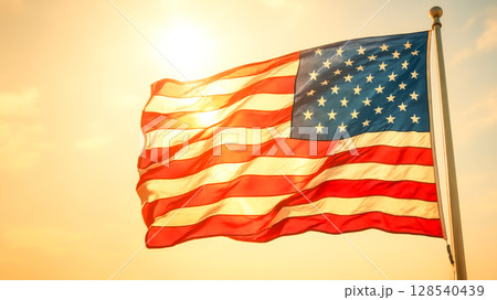 American Flag Waving Proudly At Sunset On National Holiday. Concept of Patriotism, Independence Day, Freedom Celebration, Government Events, And Traditional Americana-Inspired Visual Identity American Flag Waving Proudly At Sunset On National Holiday. Concept of Patriotism, Independence Day, Freedom Celebration, Government Events, And Traditional Americana-Inspired Visual Identity 128540439