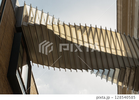 View from below of The futuristic modern of Twisted sky bridge connecting Royal opera house to Royal ballet school in Covent garden. 128540585