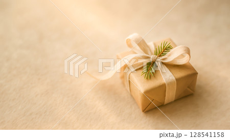 Eco Gift Box Wrapped In Kraft Paper With Ribbon And Fir Twig On Beige Fabric For Christmas Holiday Packaging Visuals. Concept Of Sustainable Wrapping, Zero Waste Celebration, And Eco-Friendly Gifting 128541158