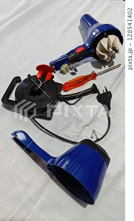 Detailed close-up of a blue electric hot air gun and tools for a DIY project on a white surface in a workshop setting Detailed close-up of a blue electric hot air gun and tools for a DIY project on a white surface in a workshop setting 128541402