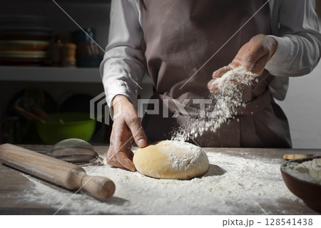 Baking concept. Caucasian female hands throwing flour at the dough. 128541438