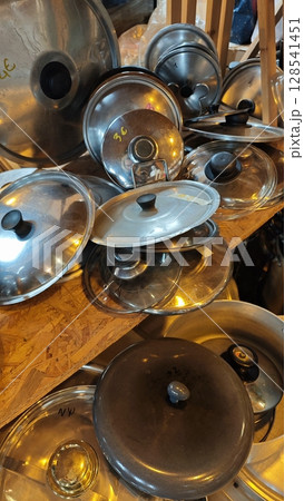 Piled collection of gleaming pot lids in a cozy workshop capturing the essence of culinary creativity and home cooking heritage 128541451