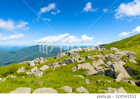 wonderful mountain landscape in summer. wide scenery with rock among grass on the hills and slopes under blue sky with fluffy clouds at high noon. scenic view of alpine environment 128541552