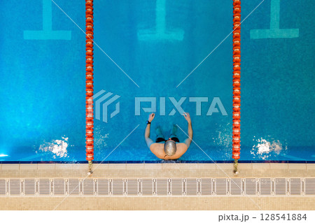 Aerial, drone top down view of professional swimmer, swimming in the swimming pool.  128541884