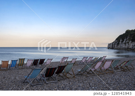 Line of deckchairs in calm bay on south coast of England Line of deckchairs in calm bay on south coast of England 128541943