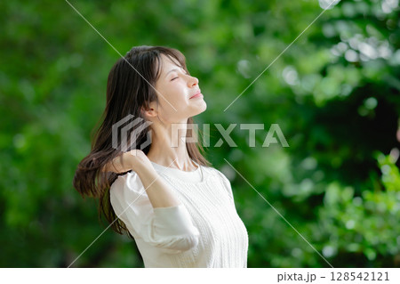 新緑の中でリラックスする女性 128542121