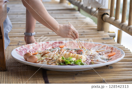 Huge Shabu is a dish made of raw pork and chicken meat, tofu, and a few vegetables. blanch in a pot of hot water. 128542313