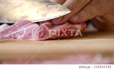Close up of chef Butcher cutting pork meat with knife on kitchen, cooking food. The chef butcher preparing pork meat for cooking. 128542330