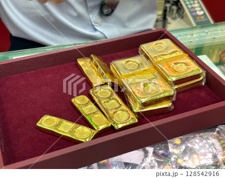 Various size of gold bar are placed on a red velvet tray. The atmosphere of trading in a gold shop. 128542916