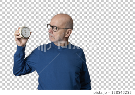 a man looks at an old alarm clock in his hand a man looks at an old alarm clock in his hand 128543253
