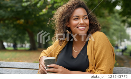 A smiling plus-size woman sitting in a park, enjoying a moment of peace with a cup of coffee 128543773