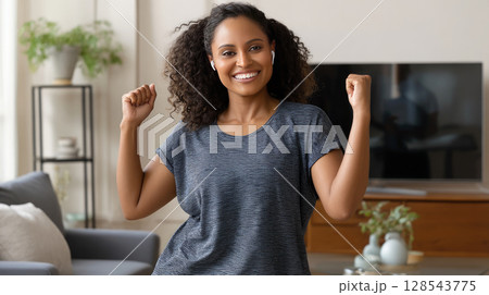 A plus-size woman working out in her living room, following a fitness video on her TV. 128543775