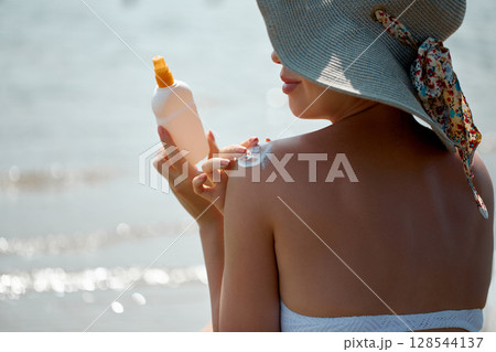 A Female  Applying Sun Cream Creme on tanned  shoulder.Sun protection.Sun Protection, girl using sunscreen to safe her skin healthy 128544137