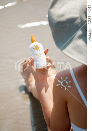 Beautiful Woman apply sun protection cream on her smooth tanned legs. Skin care. Closeup on female Hand smearing  moisturizing lotionon. Sunblock  concept 128544140