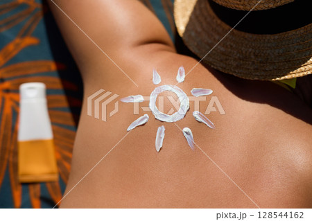 Skin care. Sun protection. Woman apply Suncream. Woman With Suntan Lotion On Beach In Form Of The Sun. Portrait Of Female With Drawn Sun On A Shoulder Skin care. Sun protection. Woman apply Suncream. Woman With Suntan Lotion On Beach In Form Of The Sun. Portrait Of Female With Drawn Sun On A Shoulder 128544162