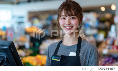 笑顔でカメラを見るスーパーの女性スタッフ 128544467