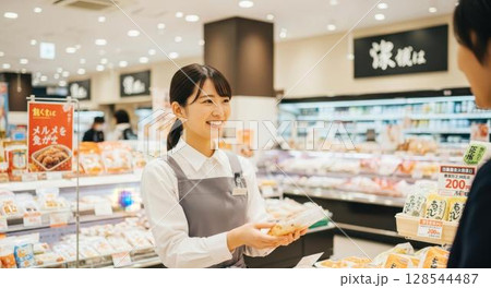 スーパーマーケットでお客様に商品を渡す笑顔の女性店員 128544487