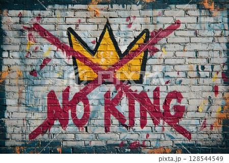 A graffiti mural on a brick wall displays a crossed-out crown and the slogan 'NO KING'. The artwork reflects protest against political policies in the USA. 128544549
