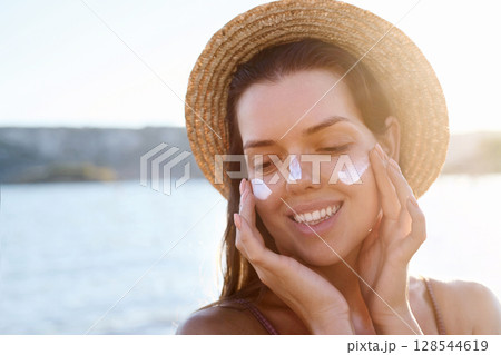 Skincare daily treatment. Beauty close up portrait of young woman with a healthy skin is applying a facial care product. Cream smear. Sun protection. Skincare daily treatment. Beauty close up portrait of young woman with a healthy skin is applying a facial care product. Cream smear. Sun protection. 128544619