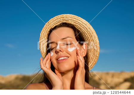 Beauty woman with suntan spf and skincare cosmetics model face portrait, woman applying lotion cream, sunscreen product. Skin and body care. A female smears moisturizing or suntan.Sun protection 128544644