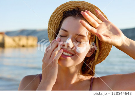 Beautiful Woman Face Portrait Beauty Skin Care Concept. Suntan Lotion Beautiful Woman Applying on beautiful on Face. Sunscreen Solar Cream. Sun protection.The Girl Uses Moisturizer Sunblock. Beautiful Woman Face Portrait Beauty Skin Care Concept. Suntan Lotion Beautiful Woman Applying on beautiful on Face. Sunscreen Solar Cream. Sun protection.The Girl Uses Moisturizer Sunblock. 128544648