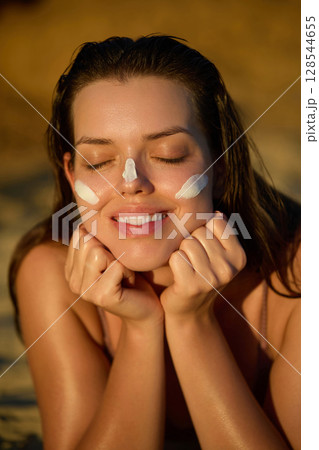 Facial treatment. Beautiful woman applying cream on face. Skin and body care. A girl smears sunscreen on her skin. Female holding suntan lotion or moisturizer. Solar cream. Cosmetology, Beauty, Spa. Facial treatment. Beautiful woman applying cream on face. Skin and body care. A girl smears sunscreen on her skin. Female holding suntan lotion or moisturizer. Solar cream. Cosmetology, Beauty, Spa. 128544655