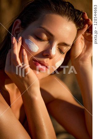 Cream, moisturizer and facial woman in skincare, beauty or cosmetics. Woman is applying a facial sunscreen product. Face daily care routine. Cream, moisturizer and facial woman in skincare, beauty or cosmetics. Woman is applying a facial sunscreen product. Face daily care routine. 128544663