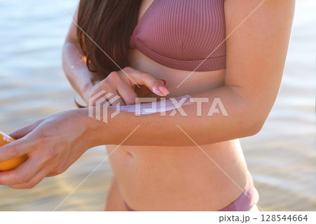 A young girl in applies sunscreen gel to her arms and shoulders, a woman takes care of her skin on a sunny day.Skin Protection and dermatology 128544664