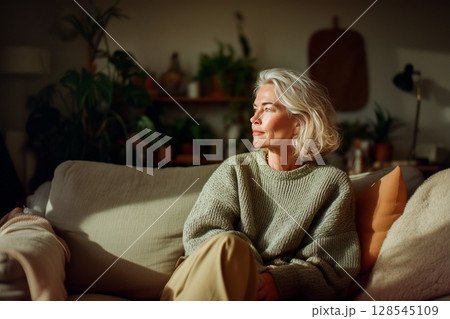 A woman is sitting on a couch in a living room A woman is sitting on a couch in a living room 128545109