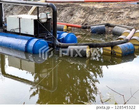 A water treatment system utilizes large blue and yellow containers while processing polluted water in a restoration effort at a water body A water treatment system utilizes large blue and yellow containers while processing polluted water in a restoration effort at a water body 128545322