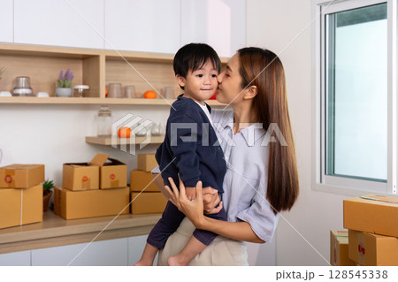 Sell Online: Loving mother embracing child while managing business 128545338