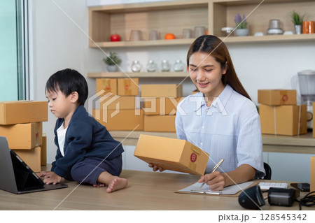 Sell Online: Busy mother managing e-commerce while caring for child 128545342