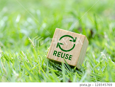 Wooden cube showing reuse symbol on grassy background 128545769