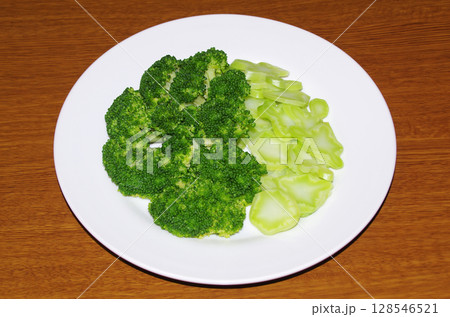 房と茎を食べやすい大きさにカットして茹でた新鮮で綺麗な緑色のブロッコリーを皿に盛った状態（木目背景） 128546521