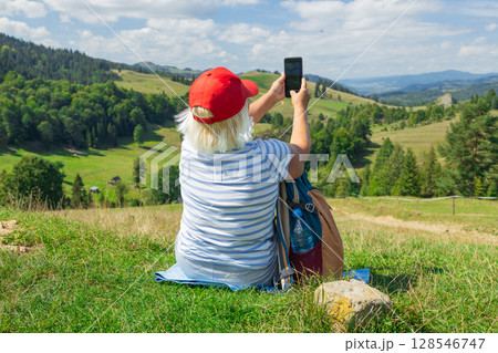 Senior Woman Taking a Selfie in Scenic Mountain Landscape Senior Woman Taking a Selfie in Scenic Mountain Landscape 128546747