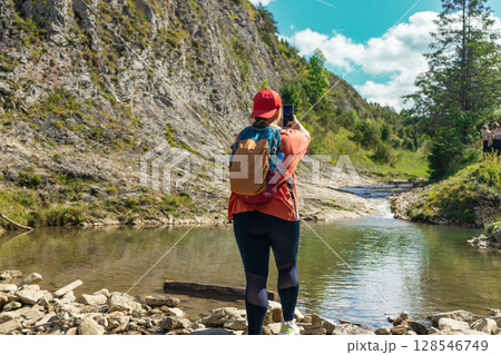 Female Hiker Taking a Selfie Near Mountain Stream in Summer 128546749