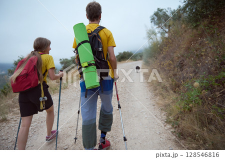 Couple Hiking in Nature with Trekking Sticks and Dog on Mountain Path 128546816