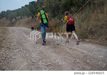 Young Couple Hiking in Nature with Trekking Poles and Dog 128546825