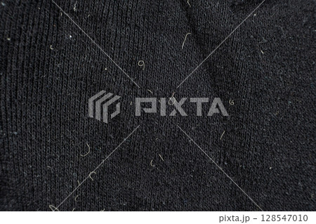 Old worn-out fabric with damaged structure, protruding threads. 128547010