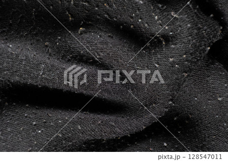 Macro texture of black fabric with lots of pilling and damage on the surface. 128547011