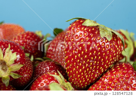 Pile of fresh ripe strawberries on a blue background. Pile of fresh ripe strawberries on a blue background. 128547128