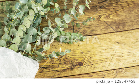 Bouquet with eucalyptus branches on wooden background. Eco friendly holiday composition with eucalypt bouquet. Wellness in the bath. Floristic background. Flat lay, copy space Bouquet with eucalyptus branches on wooden background. Eco friendly holiday composition with eucalypt bouquet. Wellness in the bath. Floristic background. Flat lay, copy space 128547459