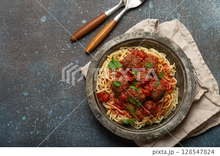 Spaghetti and meatballs with tomato sauce served on rustic plate with cutlery top view, Italian cuisine 128547824