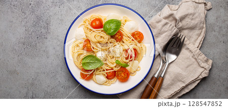 Spaghetti with cherry tomatoes and mozzarella being served on a plate with copy space 128547852