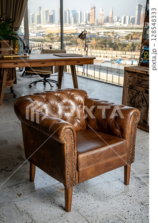 A brown leather chair with a gold trim sits in front of a window 128548333