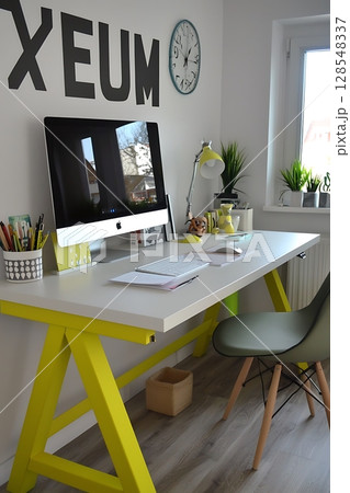 A yellow and white desk with a black and white Xeem sign on the wall 128548337