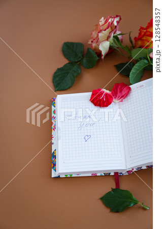 A cozy desk with flowers, frothy coffee and blank pages 128548357